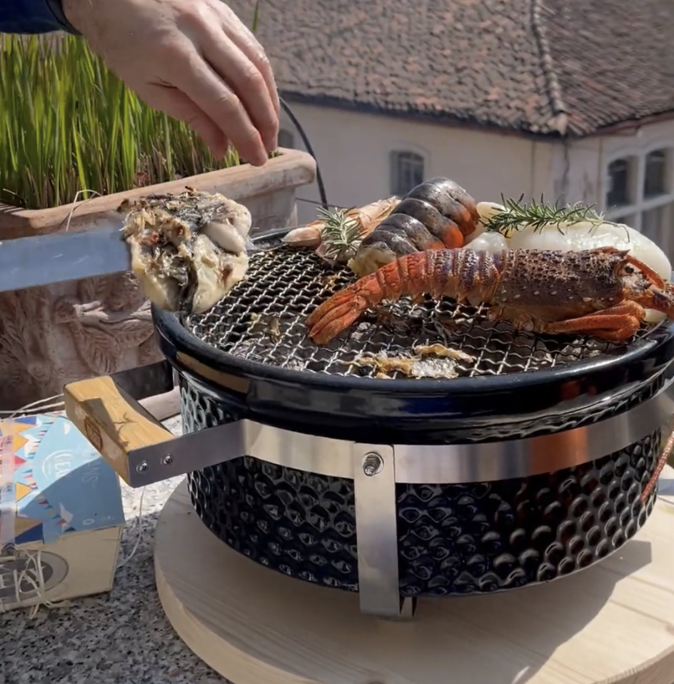 Pesce e crostacei in cottura su una griglia hibachi in ceramica all aperto